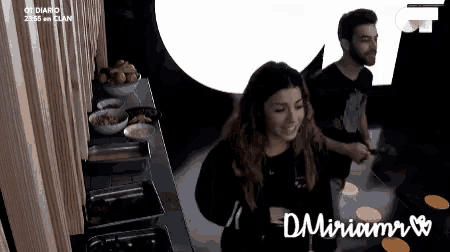 a man and a woman are standing next to each other in a kitchen and the woman 's name is miriam