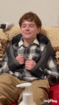 a man in a plaid shirt is sitting on a couch with a massager around his neck .