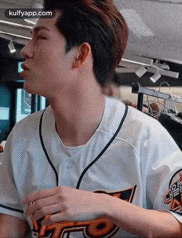 a young man wearing a baseball uniform is standing in a room .
