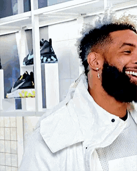 a man with a beard wearing a white jacket and earrings