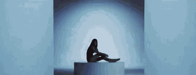 a woman in a black bodysuit is sitting on top of a white circle .