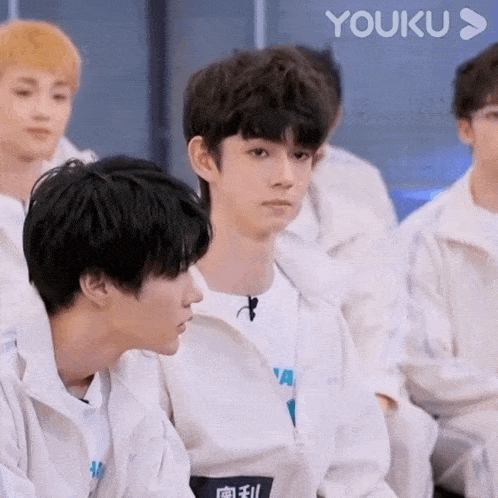 a group of young men are sitting in a row and one of them is looking at the camera .