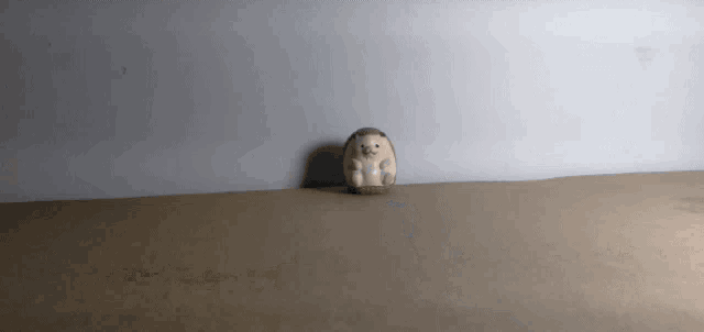 a stuffed hedgehog is sitting on a brown carpet