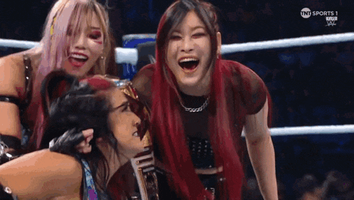 a group of female wrestlers are posing for a picture in a wrestling ring .