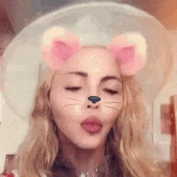 a close up of a woman wearing a cat mask with a hat on .