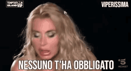 a woman with blonde hair is making a funny face and saying `` nessun t 'ha obbligatorio '' .
