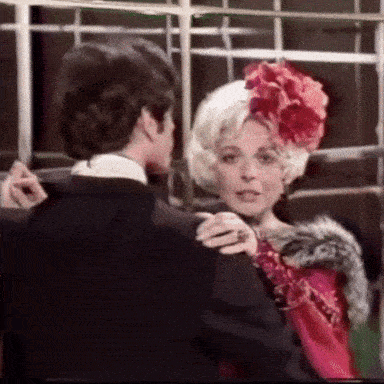 a man and woman are dancing together and the woman is wearing a red dress and a red flower in her hair .