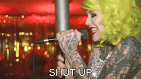 a woman with green hair is singing into a microphone with the word shut up written below her