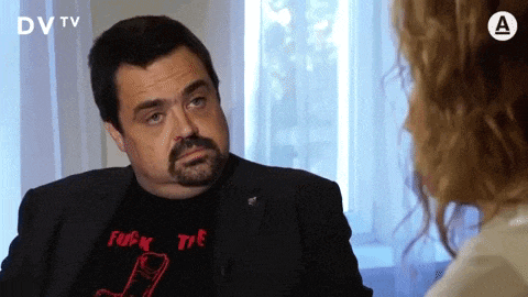 a man wearing a black shirt that says " fuck the tv "