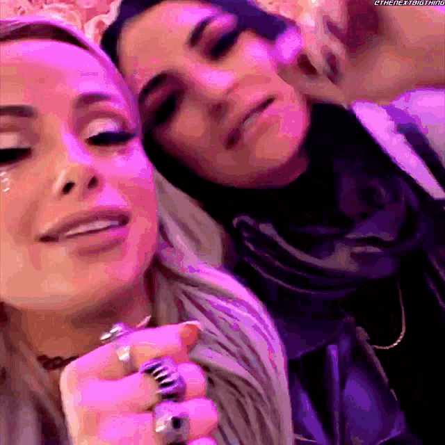 a couple of women are posing for a picture with purple lights behind them .