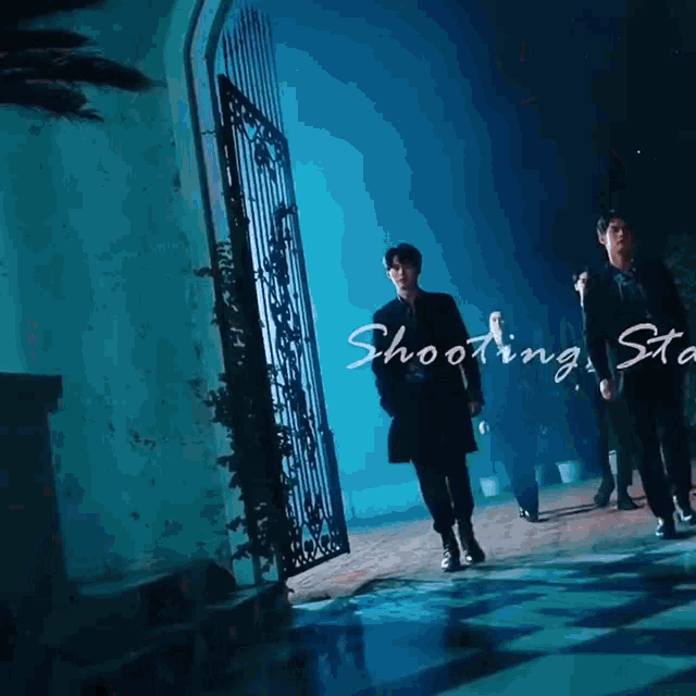 a group of men are standing in front of a gate that says shooting star on it
