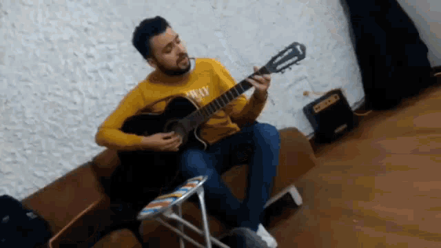 a man wearing a yellow sweater that says norway is playing a guitar
