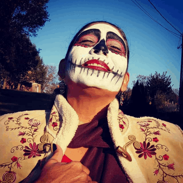 a woman with a day of the dead face painted on her face