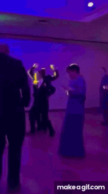a bride and groom are dancing at a wedding reception in a dark room