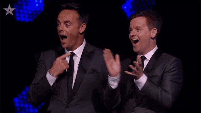 two men in suits and ties are clapping their hands in front of a star