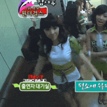 a group of girls are standing in a room with a sign that says music bank on it