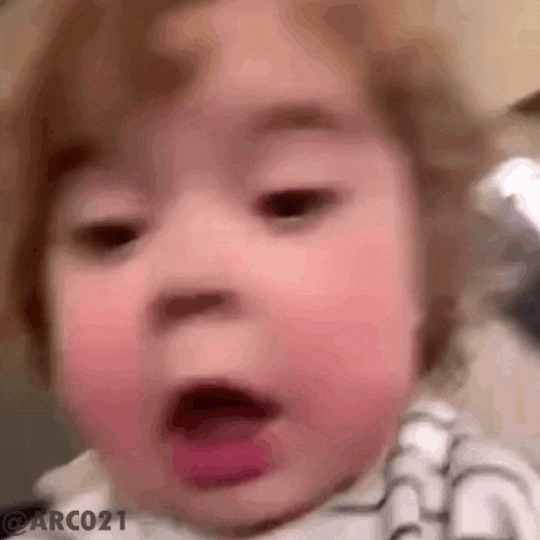 a baby is making a funny face with his mouth open and his tongue out .