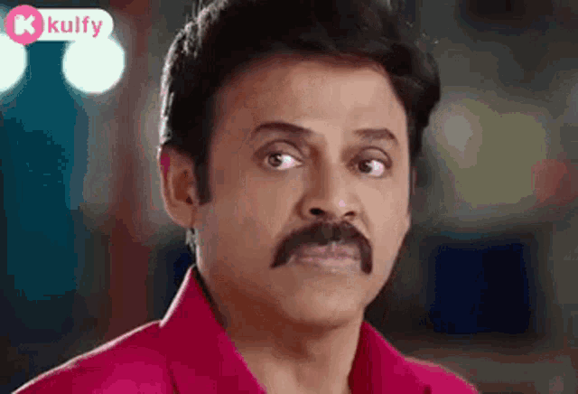 a man with a mustache and a red shirt is looking at the camera .