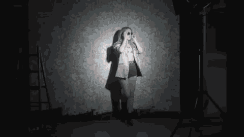 a woman is standing in front of a wall in a dark room with a flashlight .
