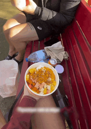 a person sitting on a bench with a bowl of food