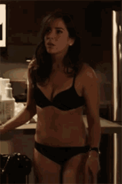 a woman in lingerie is standing in a kitchen .