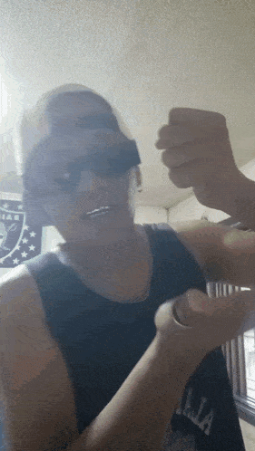 a man wearing a hat and sunglasses holds his fist in the air