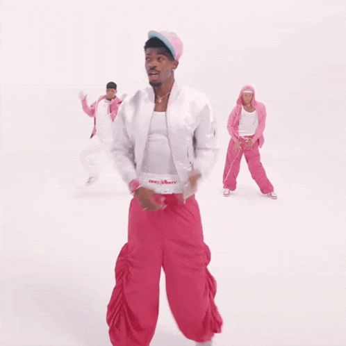 a man in a white jacket and pink pants is dancing with two other people