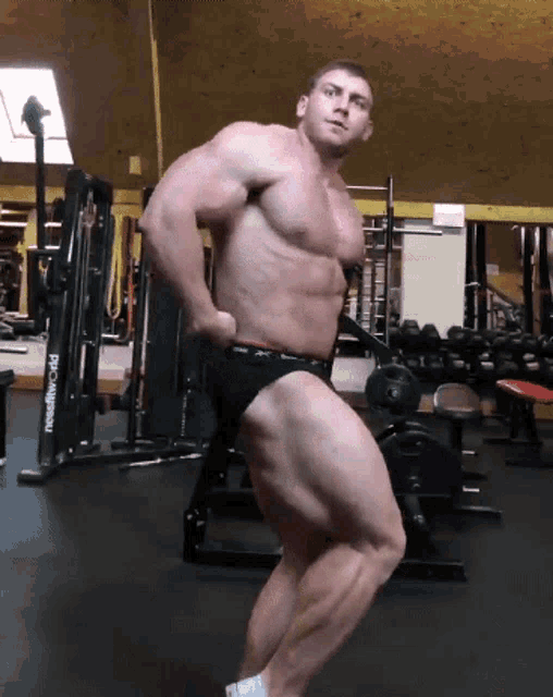 a bodybuilder poses in front of a machine that says needliftworld on it