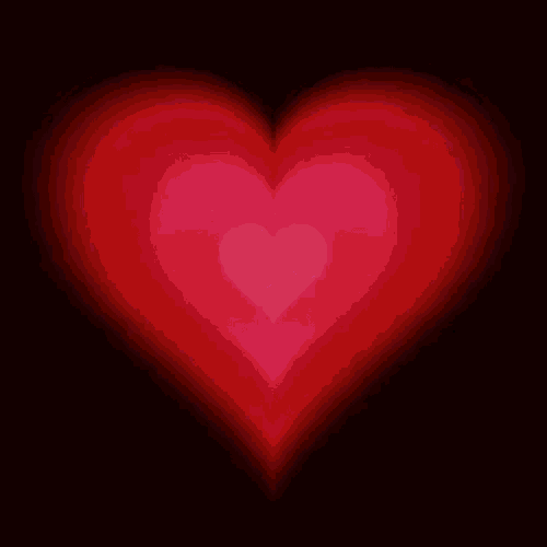 a red heart is glowing in the dark on a black background