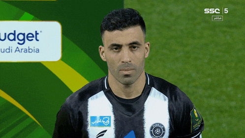 a soccer player stands in front of a sign that says budget