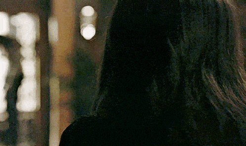 a woman with long dark hair is standing in front of a mirror looking at herself .