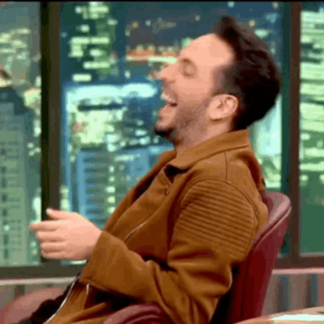 a man in a brown jacket is laughing with his mouth wide open