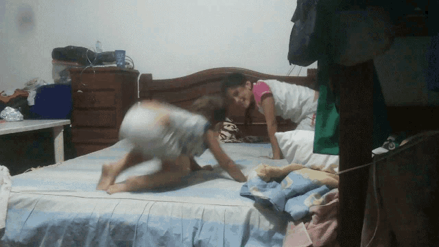 a boy and a girl are playing on a bed and the girl is wearing a shirt that says ' i love you '