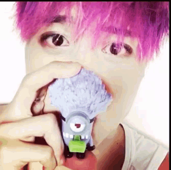 a man with pink hair is holding a toy in his mouth