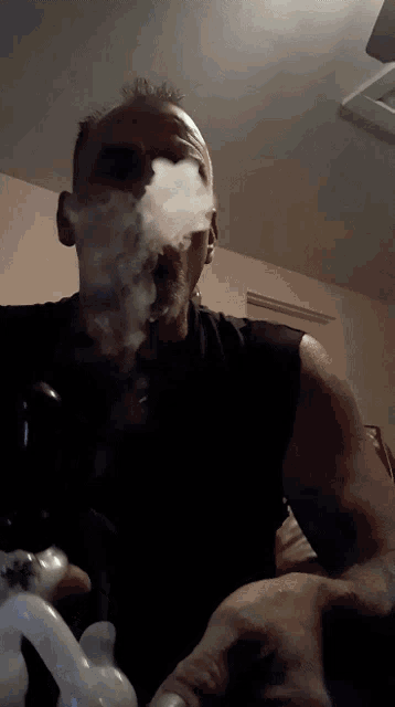 a man in a black tank top is smoking a pipe