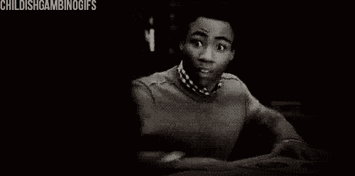 a black and white photo of a man making a funny face while sitting at a table .