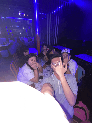 a group of people sitting around a table with one wearing a hat that says ' abercrombie & fitch '