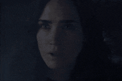 a close up of a woman 's face with a surprised look on her face in the dark .