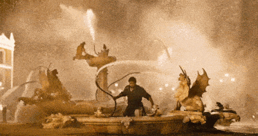 a man is standing in front of a fountain with a statue of a dragon