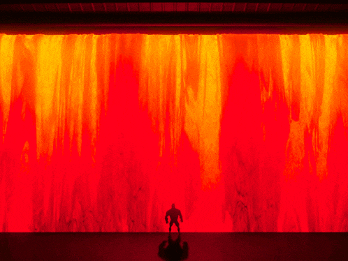 a silhouette of a man standing in front of a red and orange background