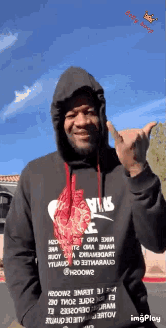 a man wearing a black nike hoodie is giving a middle finger