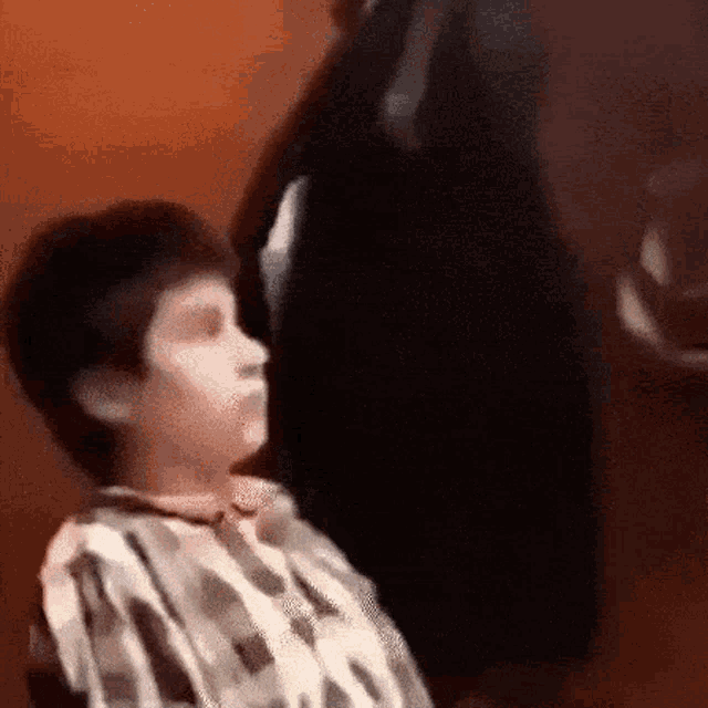 a young boy in a camo shirt is looking up at something