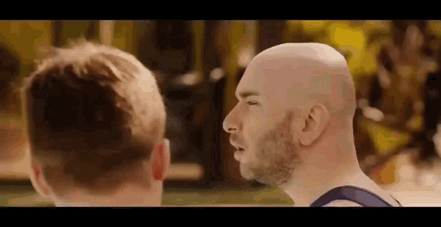 a bald man with a beard is standing next to another bald man .