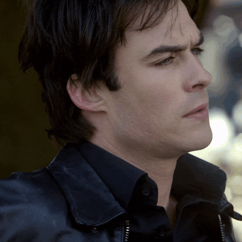 a close up of a man 's face with a black shirt and a black jacket