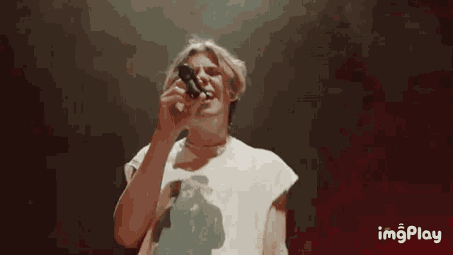 a man is singing into a microphone while wearing a t-shirt with a picture of a woman on it .