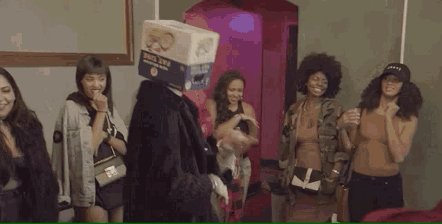 a man with a box on his head is dancing in front of a group of people .