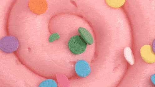 a cookie with pink frosting and sprinkles on a pink surface