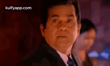 a man in a suit and tie is standing in front of a woman in a dark room .