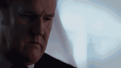 a close up of a man in a suit and tie making a serious face .