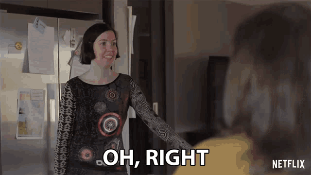 a woman is standing in front of a refrigerator talking to another woman and saying oh right .
